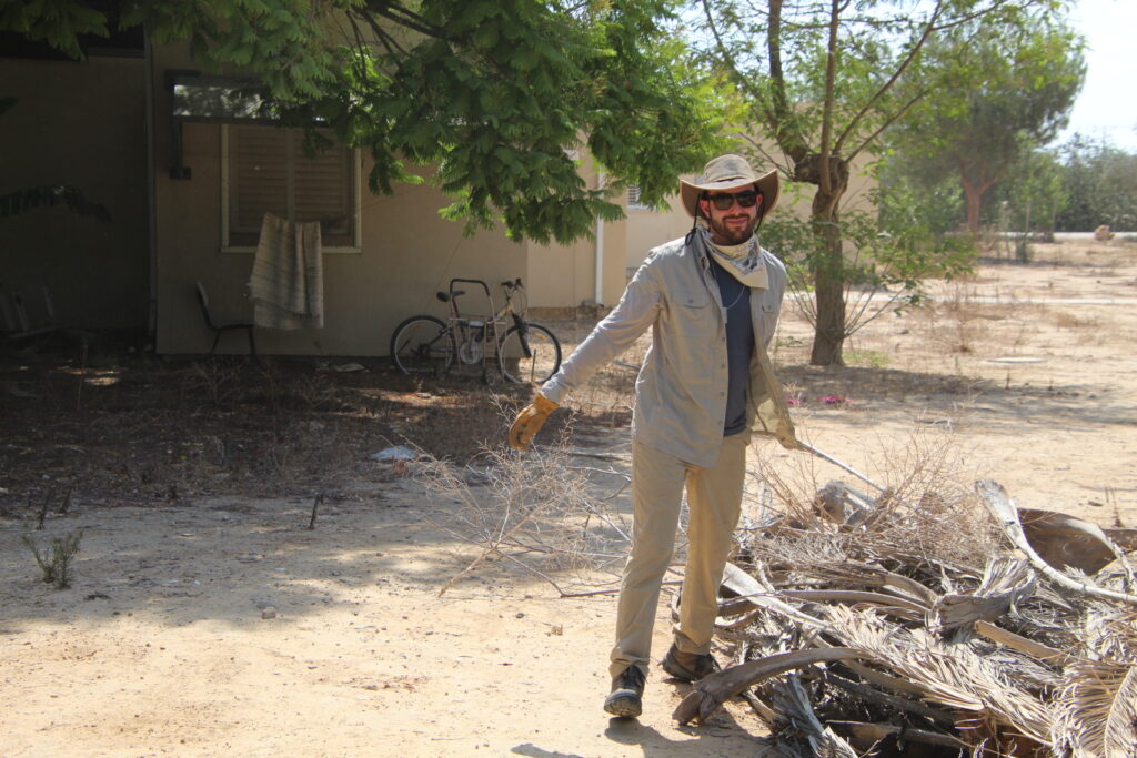 Man with workers gloves clears brush from Kibbutz attacked on October 7