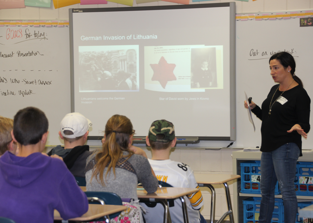 Woman stands before whiteboard teaching a class